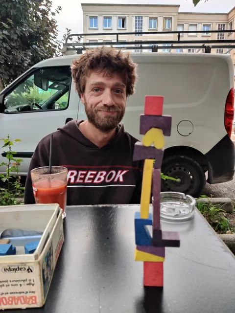 Clément Lemaire, souriant, derrière une tour de blocs de bois